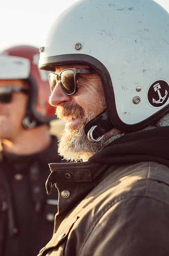 Middle aged bearded motorcycle rider in white open faced helmet.